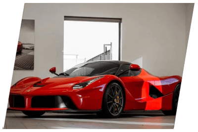 A red sports car is parked in front of a window.